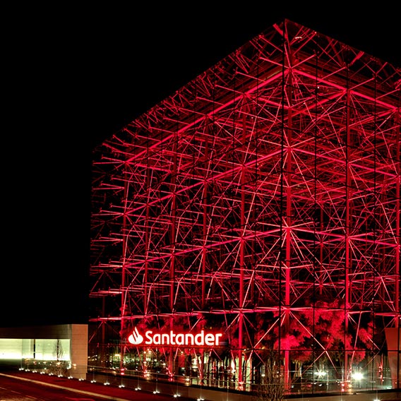 Illuminated Santander Bank headquarters building at night, showcasing modern architecture